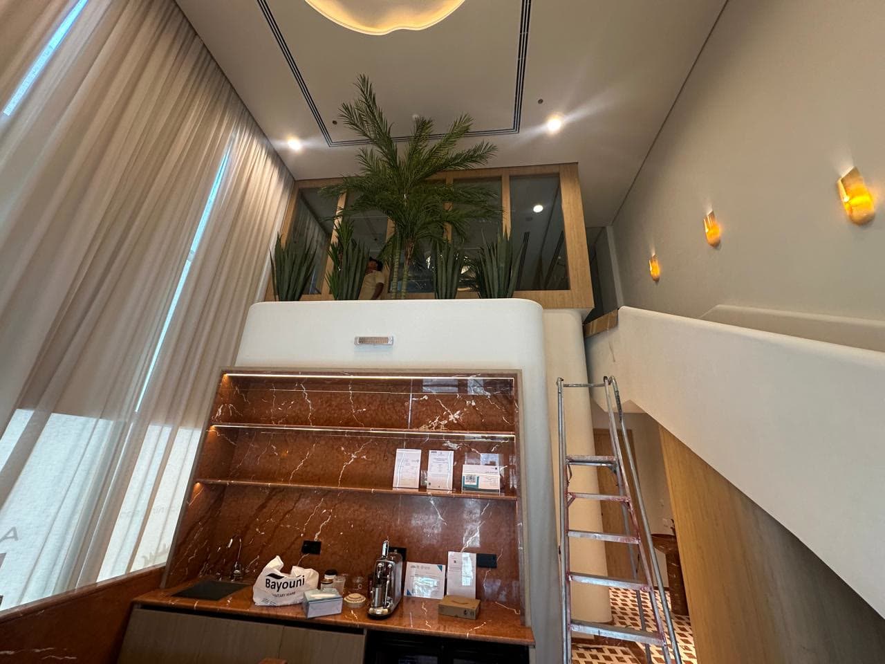 Reception hall with palms, scalloped ceiling light and marble counter