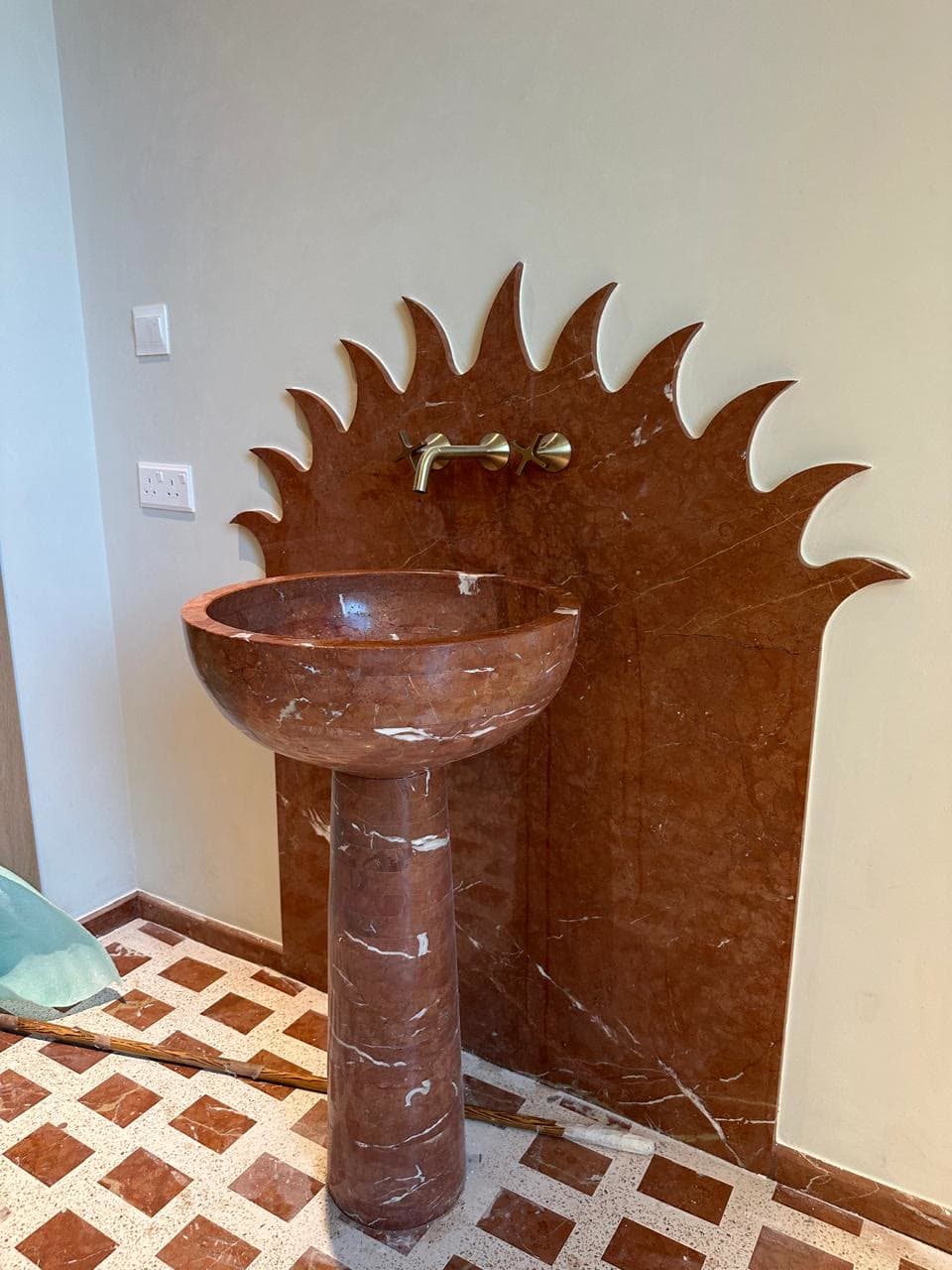 Hand-cut red marble basin with a sunburst backsplash