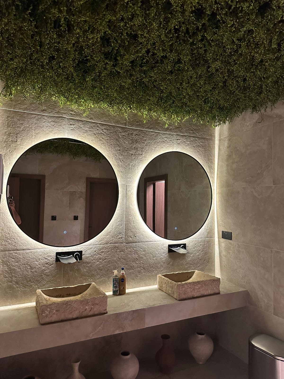 Spa washroom with backlit round mirrors and stone vanities