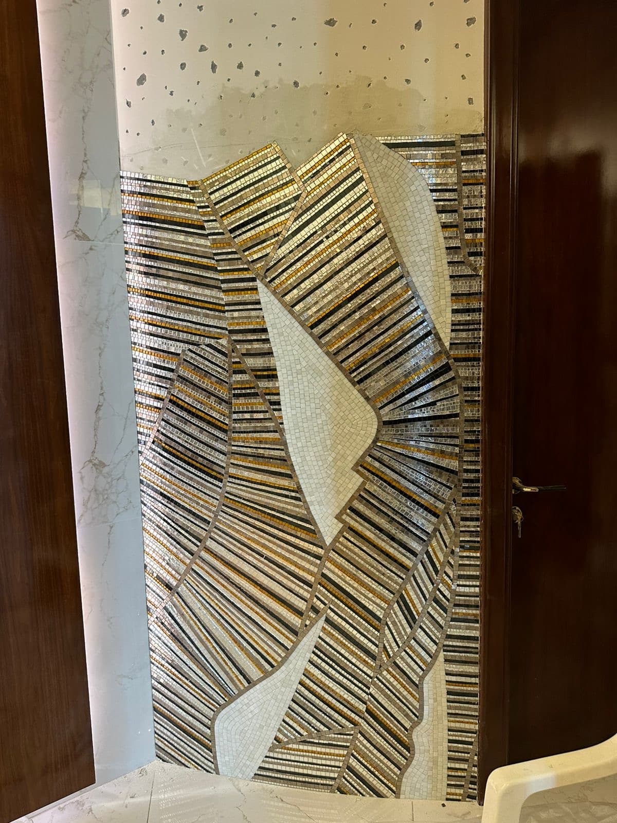 Hand-laid mosaic feature wall in stone, silver and amber tones