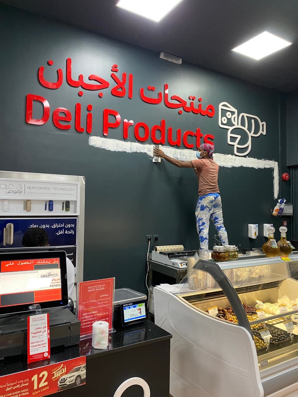 Sign-writer painting the deli products lettering